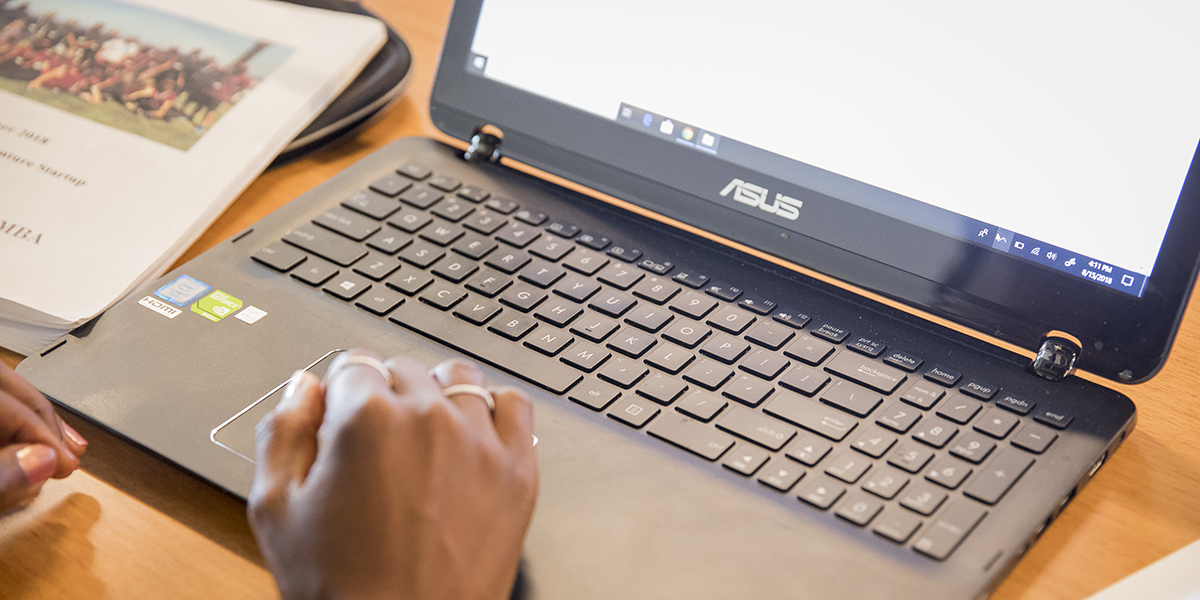 A close-up of a laptop with an individual's hands on the keyboard.